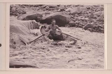 Norm Nevills at 13 Foot Rapid, San Juan River. The boat is one of Ansel Hall's folding spruce skiffs and the river flow is less than 400 cfs